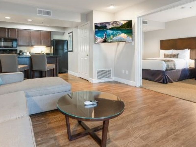 A wide view of a hotel suite showing a kitchenette, living area, and bedroom.