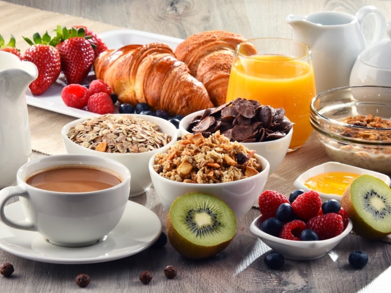 A breakfast spread with pastries, fruit, and bowls of cereal