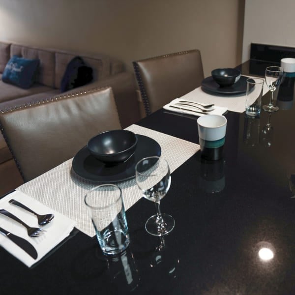 A dining table set for a meal with black plates, glasses, and silverware.